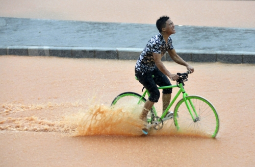 5月11日，一名行人在深圳街頭冒雨騎行。