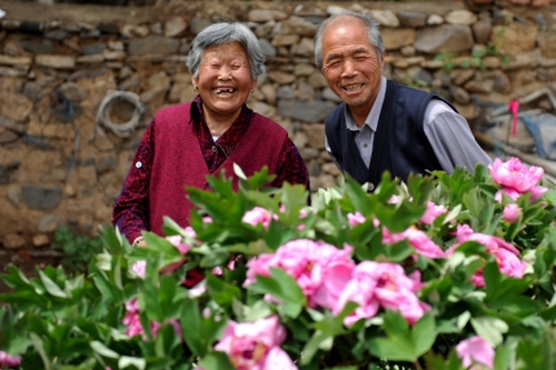 　5月13日，許潤枕（右）和老伴兒董振賢在牡丹花前合影。