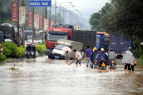 5月18日，國(guó)道324線廣西興業(yè)縣石南鎮(zhèn)黑石嶺路段被洪水淹沒(méi)，一名群眾手持木棍為摩托車探路。