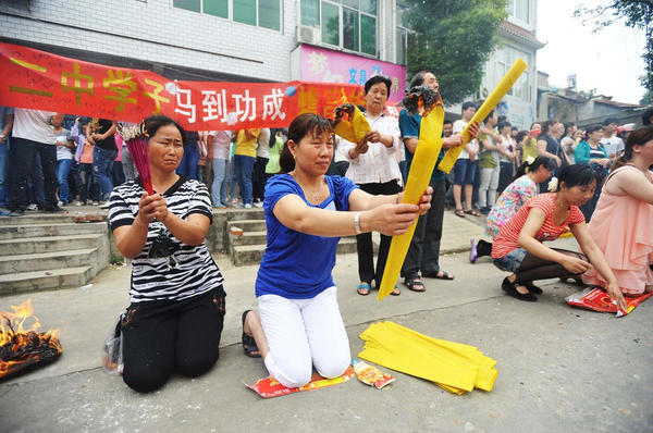 　送考家長(zhǎng)和村民燒紙跪拜。