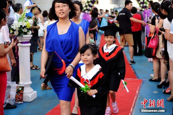 6月28日，山東青島開(kāi)發(fā)區(qū)第一幼兒園怡和嘉園分園2014級(jí)大班舉行畢業(yè)典禮，全體畢業(yè)生身著學(xué)士服在盛裝父母的陪同下，依次走過(guò)紅毯，在畢業(yè)榜上鄭重簽下自己的名字，其氣勢(shì)不輸當(dāng)紅影星紅毯秀。中新社發(fā) 俞方平 攝 圖片來(lái)源：CNSPHOTO