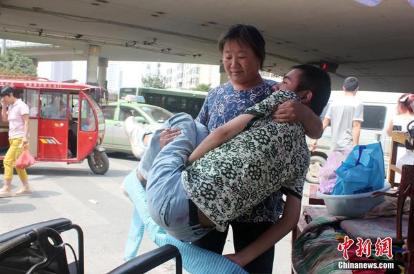 來到街頭“賣唱”點(diǎn)，呂愛梅熟練地把兒子把下三輪車，布置場(chǎng)地。 馬義恒 攝