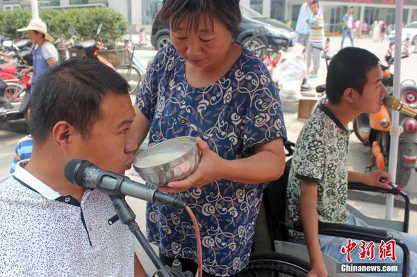 每天起床后便匆匆來到街頭“賣唱”，呂愛梅只能把面湯熬好在小強(qiáng)和小猛唱歌間隙喂他們吃。馬義恒 攝