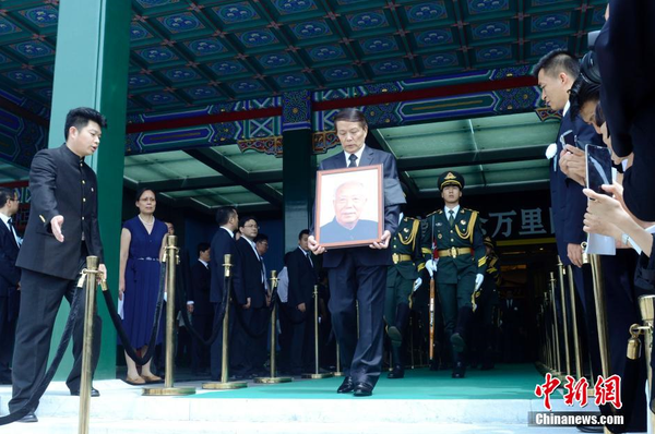 7月22日，萬里遺體在北京火化，社會各界人士前往八寶山殯儀館進(jìn)行悼念。圖為萬里兒子萬伯翱手捧遺像步出。 中新社發(fā) 盛佳鵬 攝