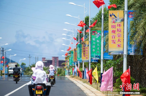 6月24日，海南省文昌市龍樓鎮(zhèn)街道兩側(cè)五星紅旗迎風(fēng)飄揚(yáng)，火箭“首發(fā)”宣傳廣告隨處可見(jiàn)。長(zhǎng)征七號(hào)運(yùn)載火箭發(fā)射日期臨近，中國(guó)首個(gè)濱海航天發(fā)射中心——文昌航天發(fā)射場(chǎng)所在地海南省文昌市龍樓鎮(zhèn)將迎來(lái)“首發(fā)”，中國(guó)的“卡納維拉爾角”正揭開(kāi)神秘面紗。中新社記者 駱云飛 攝