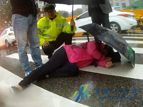 江蘇徐州女子雨中被撞倒地 民警為其撐傘遮雨