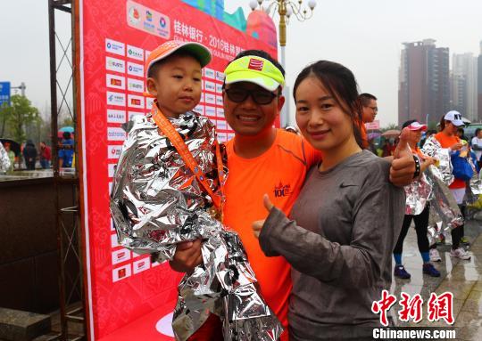 來自廣州的李強(qiáng)夫婦用兒童車，載著4歲的兒子，一家三口完成了在桂林舉行的半程馬拉松比賽?！W惠蘭 攝