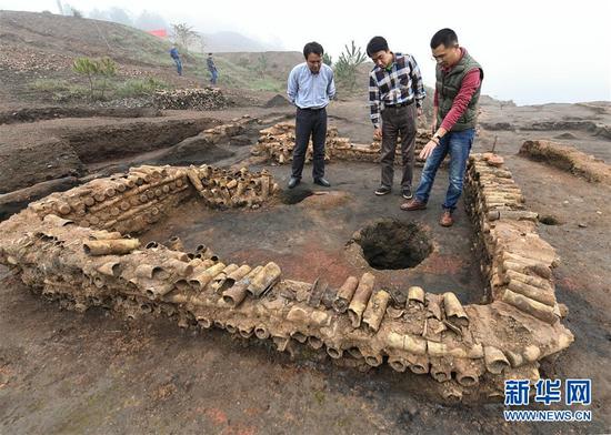 在桐木嶺礦冶遺址，考古人員查看用廢棄坩堝壘筑的房屋遺址（11月18日攝）。