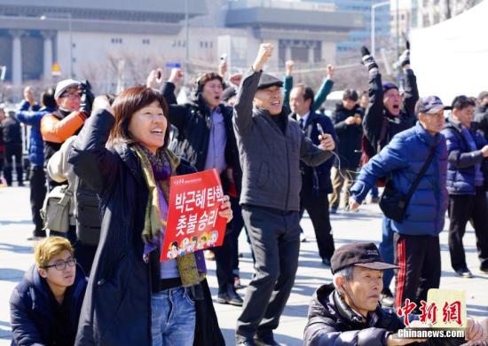 3月10日，在象征著韓國(guó)政治中心的首爾光化門廣場(chǎng)，民眾在聽(tīng)到憲法法院對(duì)總統(tǒng)樸槿惠彈劾案的審判結(jié)果后歡呼。韓國(guó)憲法法院當(dāng)日作出裁決，宣布彈劾案成立。樸槿惠成為韓國(guó)歷史上首位被彈劾罷免的總統(tǒng)。<a target='_blank' href='http://www.chinanews.com/'>中新社</a>記者 吳旭 攝