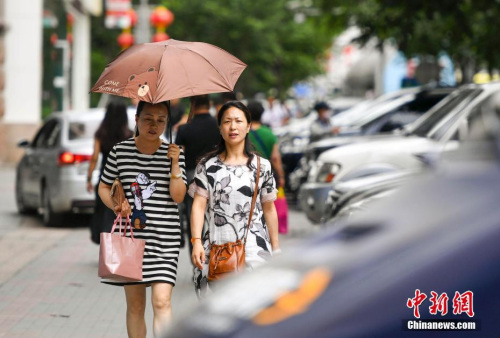 新疆烏魯木齊市街頭，民眾打傘抵擋高溫天氣。