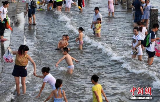 7月4日傍晚，市民們帶著小孩在海邊戲水消暑。連日來，受副熱帶高壓影響廈門地區(qū)持續(xù)高溫。 張斌 攝