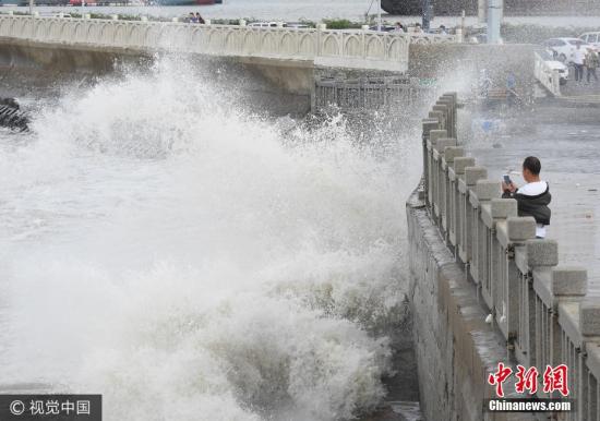 10月2日，游客在連云港市連云區(qū)海岸邊觀賞巨浪。當日，受冷空氣影響，江蘇連云港沿海出現(xiàn)大風，海濱掀起陣陣巨浪。據(jù)中央氣象臺預報，10月1日夜間至4日，冷空氣將自北向南影響我國中東部大部地區(qū)，長江中下游及其以北地區(qū)有4-5級風，陣風6-7級，日平均氣溫或最低氣溫將下降4-6℃，北方部分地區(qū)降溫幅度可達10℃以上。耿玉和 攝 圖片來源：視覺中國