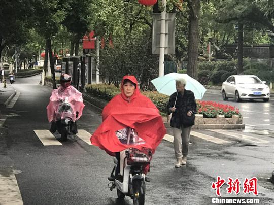 11日，南京迎來降溫降雨。圖為市民披上雨衣出行?！铑伌?攝