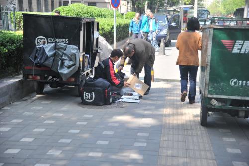 圖為快遞小哥在路邊配送快遞。呂春榮 攝