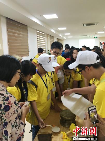 圖為華裔青少年當(dāng)日在廣西自治區(qū)博物館人員的指導(dǎo)下嘗試拓印一面小的銅鼓。鐘建珊 攝