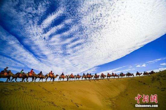 資料圖：甘肅敦煌鳴沙山月牙泉景區(qū)藍(lán)天、白云、黃沙相映成趣，每天吸引數(shù)萬中外游客觀光游覽。 王斌銀 攝