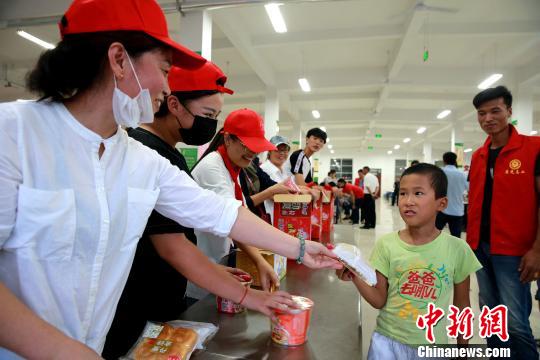 8月24日，志愿者在濰坊壽光市營里鎮(zhèn)第二初級中學(xué)安置點(diǎn)為災(zāi)民發(fā)放救援物資?！×籂?攝