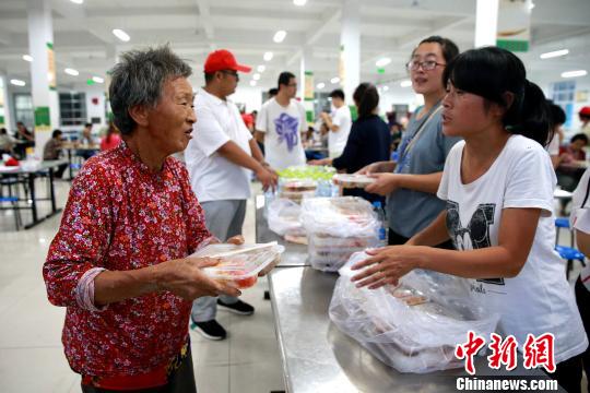 8月24日，志愿者在濰坊壽光市營里鎮(zhèn)第二初級中學(xué)安置點(diǎn)為災(zāi)民發(fā)放救援物資?！×籂?攝