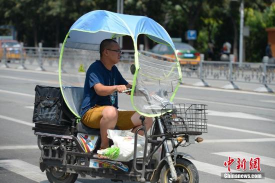 資料圖：男子在電動(dòng)車(chē)上撐起遮陽(yáng)棚。<a target='_blank' href='http://www.chinanews.com/'>中新社</a>記者 劉文華 攝