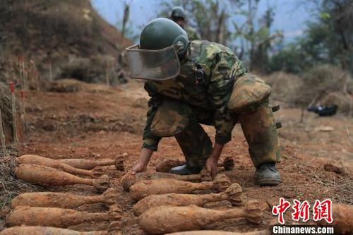 中國人民解放軍南部戰(zhàn)區(qū)陸軍云南掃雷大隊在雷場掃雷期間，一名戰(zhàn)士將一枚搜排出來的炮彈放至臨時存放點(diǎn)。　楊萌 攝