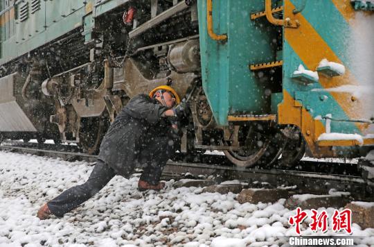 南京東機務(wù)段機車乘務(wù)員強化雪天機車走行部、車鉤等關(guān)鍵部件檢查，確保機車質(zhì)量良好，途中運輸安全。　劉金建 攝