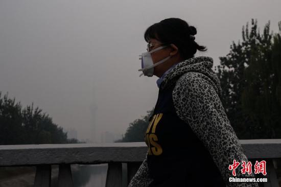 資料圖：北京一名市民戴防霾口罩在戶外行走，遠(yuǎn)處的中央電視塔亦被霧霾籠罩。<a target='_blank' href='http://www.chinanews.com/'>中新社</a>記者 崔楠 攝