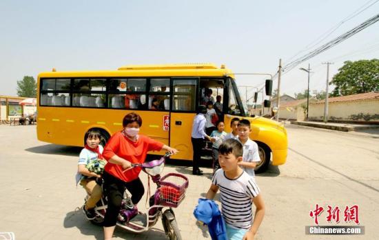 資料圖：學(xué)生家長接送從校車上下來的學(xué)生。 張道正 攝