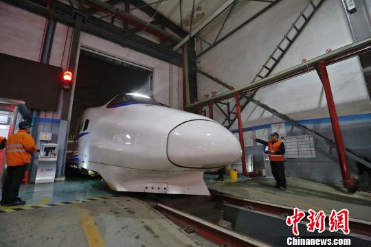 一列動車組駛?cè)胲噹?，機械師位列兩邊檢查車體外觀?！《〔?攝