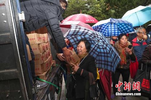 資料圖：上海百名居民在雨中排成一條長龍，領(lǐng)取剛到貨的秭歸臍橙。供圖