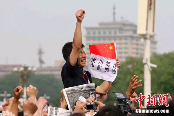 2008年5月19日，北京天安門廣場上的民眾為地震遇難者默哀，一位來自四川的男子高舉右手為家鄉(xiāng)加油。中新社記者 富田 攝