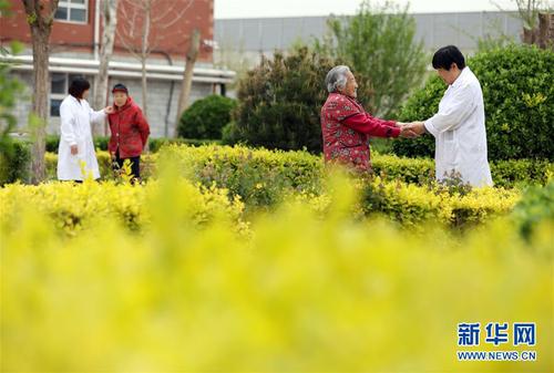 5月5日，在河北省衡水市桃城區(qū)一家養(yǎng)老康復(fù)醫(yī)療中心，護(hù)工在陪老人散步。新華社記者 牟宇 攝